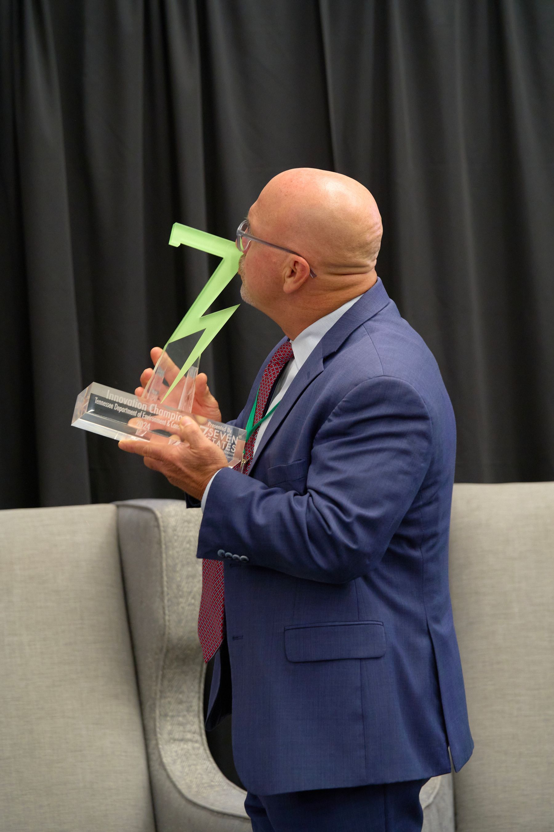 A man in a suit and tie is holding a trophy.