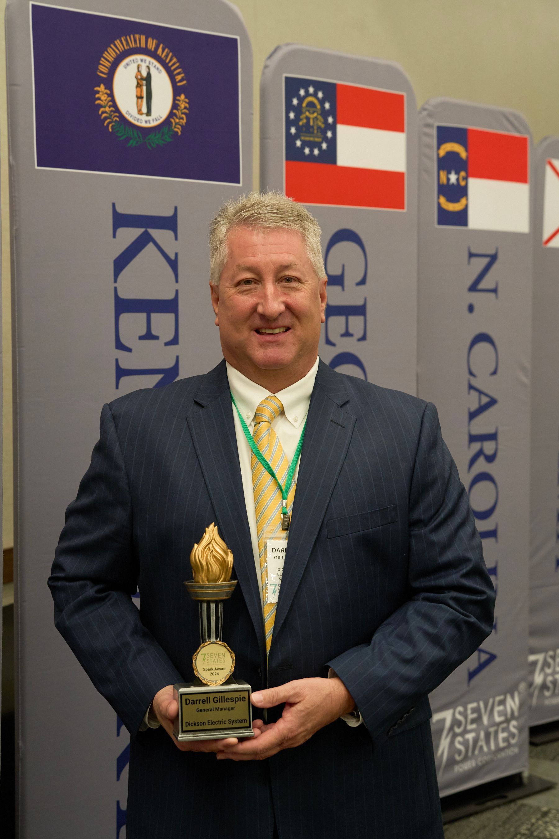 A man in a suit and tie is holding a trophy
