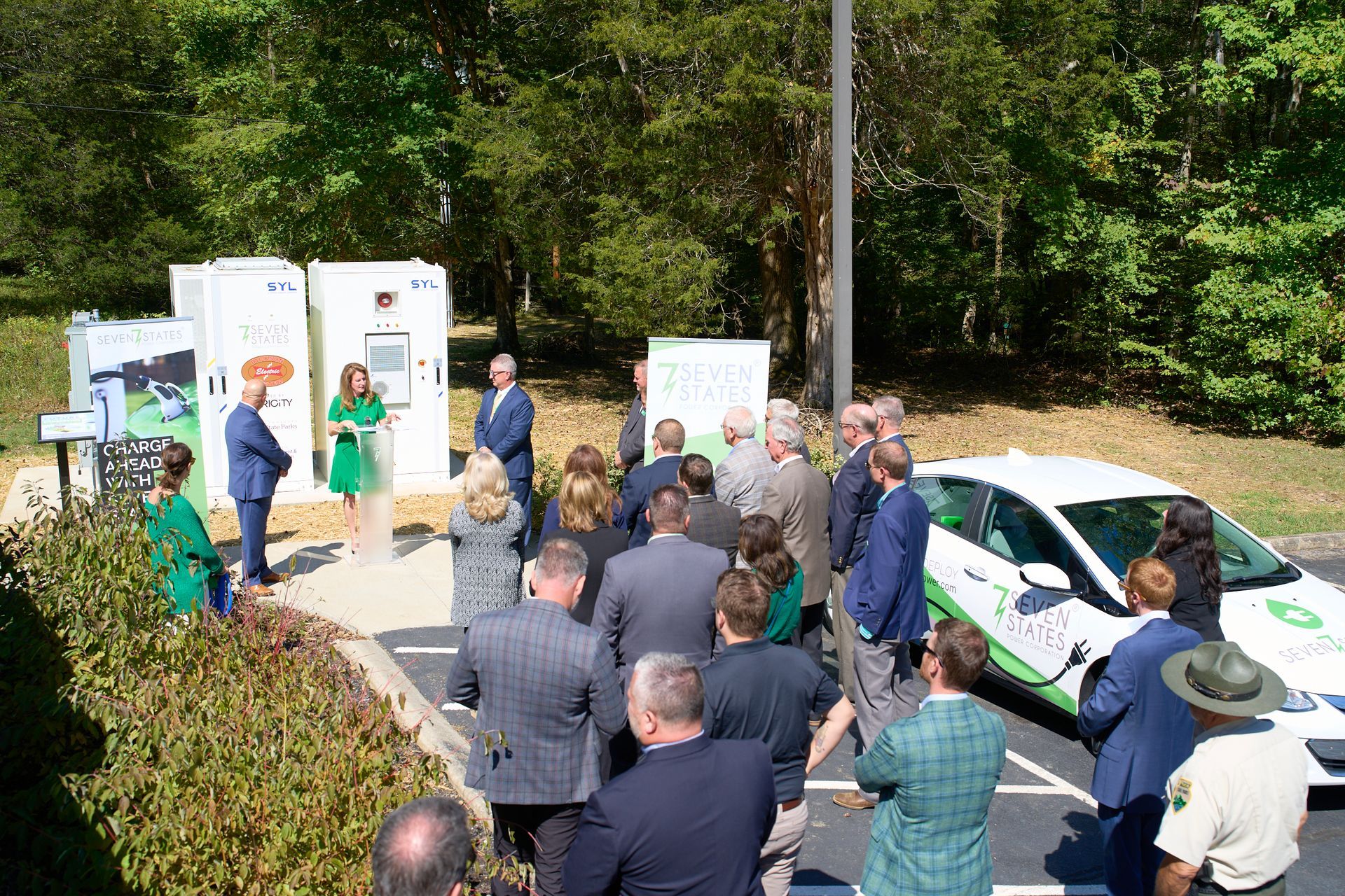 A group of people are standing in front of two electric cars.