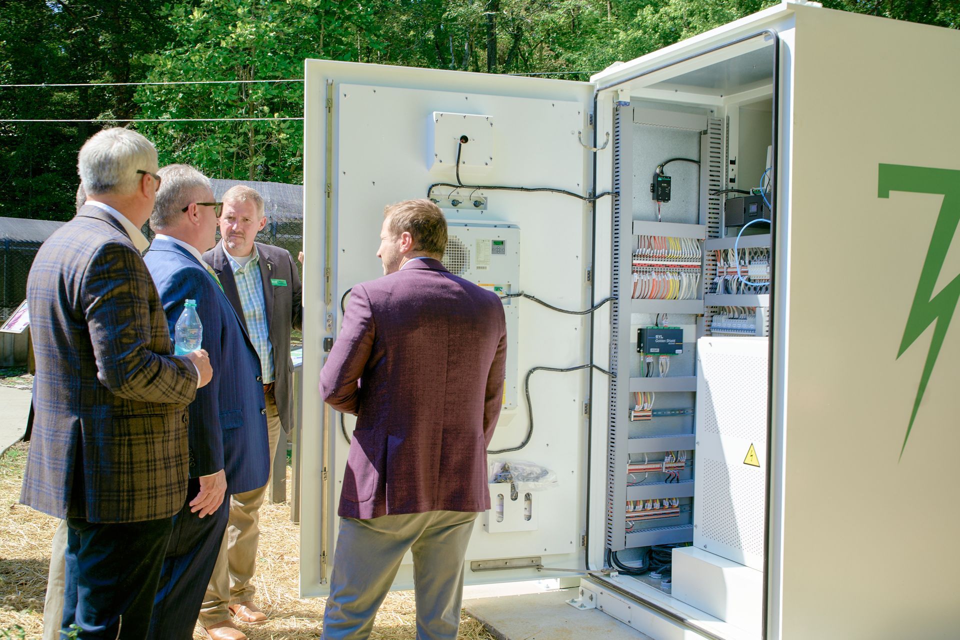 A group of men are standing around a white box with a lightning bolt on it.
