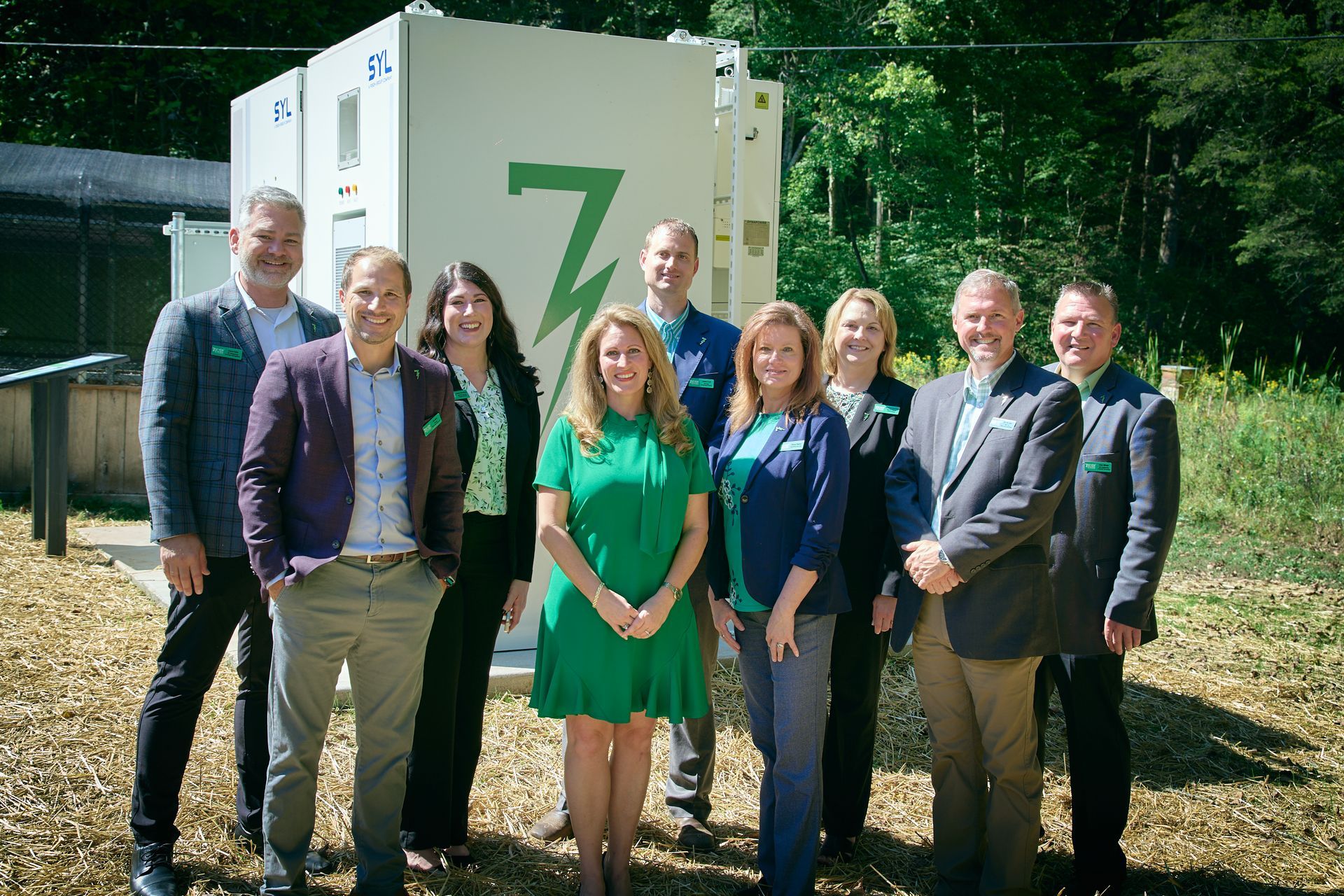 A group of people are posing for a picture in front of a building with the letter z on it.
