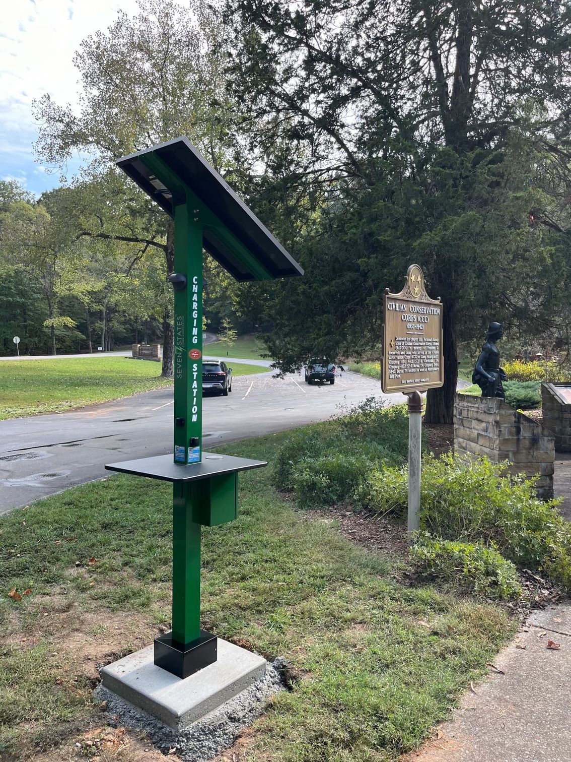 A green solar panel is sitting on the side of the road next to a sign.