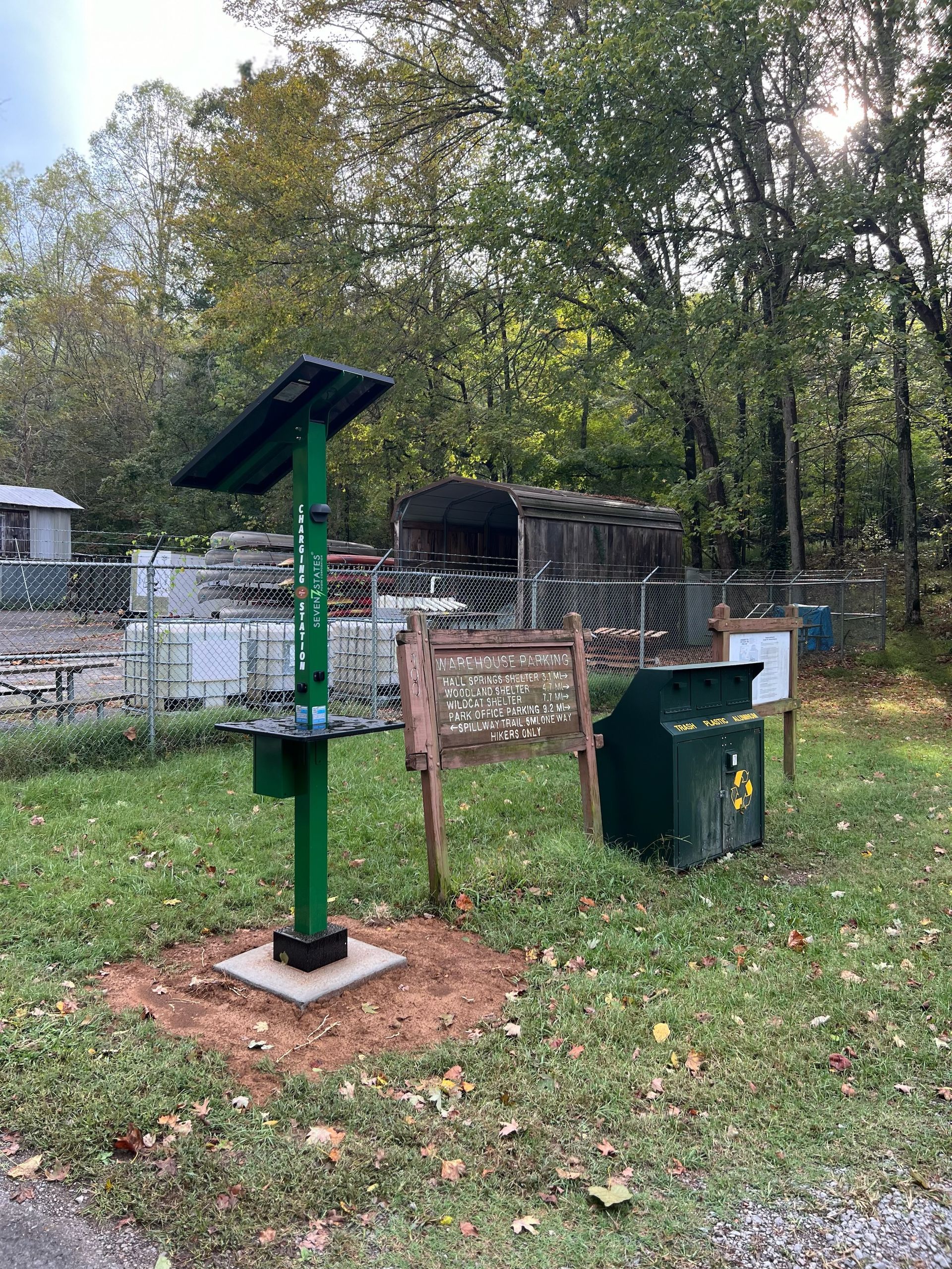 A green pole with a solar panel on top of it is in the middle of a grassy field.