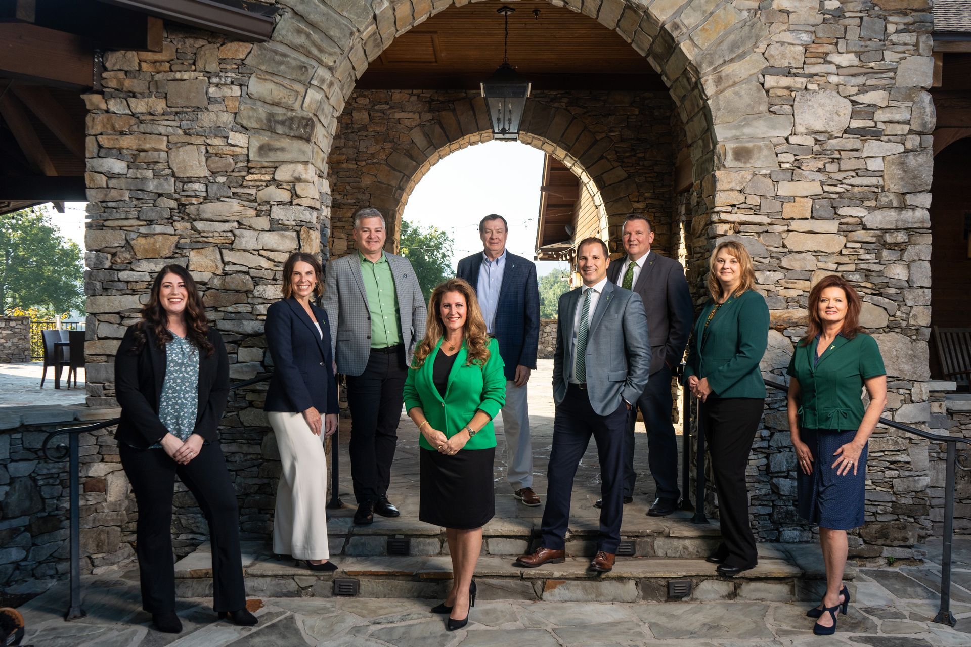 A group of people standing next to each other in front of a stone archway.