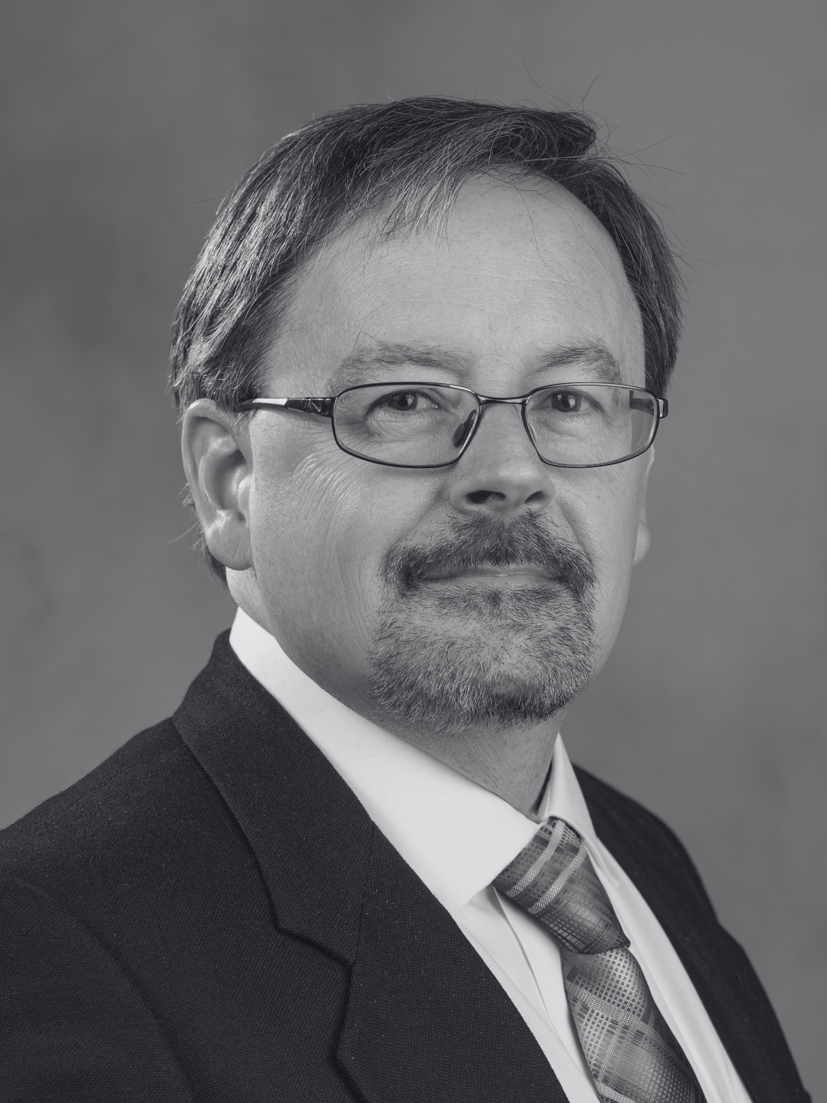 A man in a suit and tie is smiling in a black and white photo.