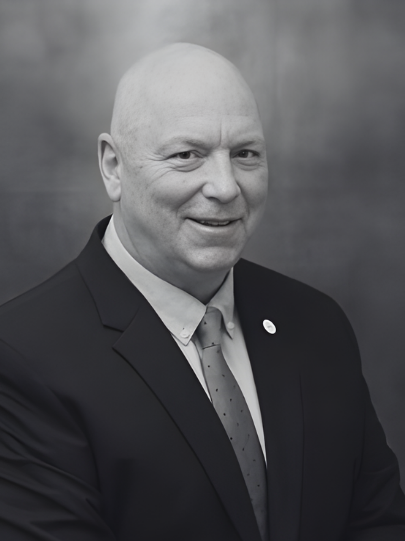 A man in a suit and tie is smiling in a black and white photo.