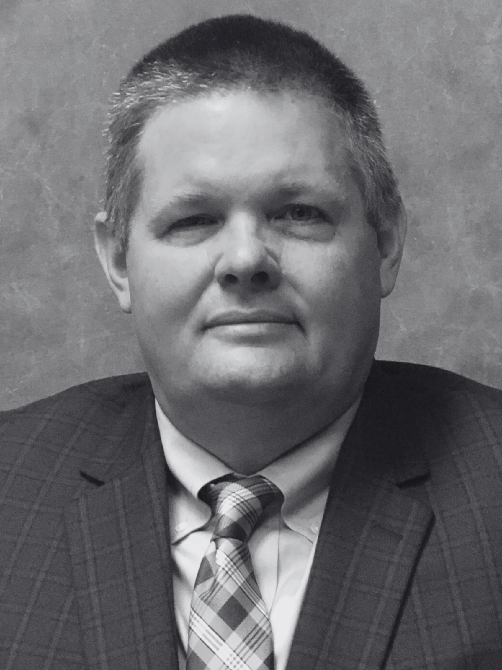 A man in a suit and tie is smiling in a black and white photo.