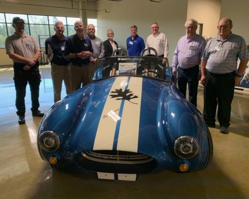 A group of men standing around a blue and white sports car