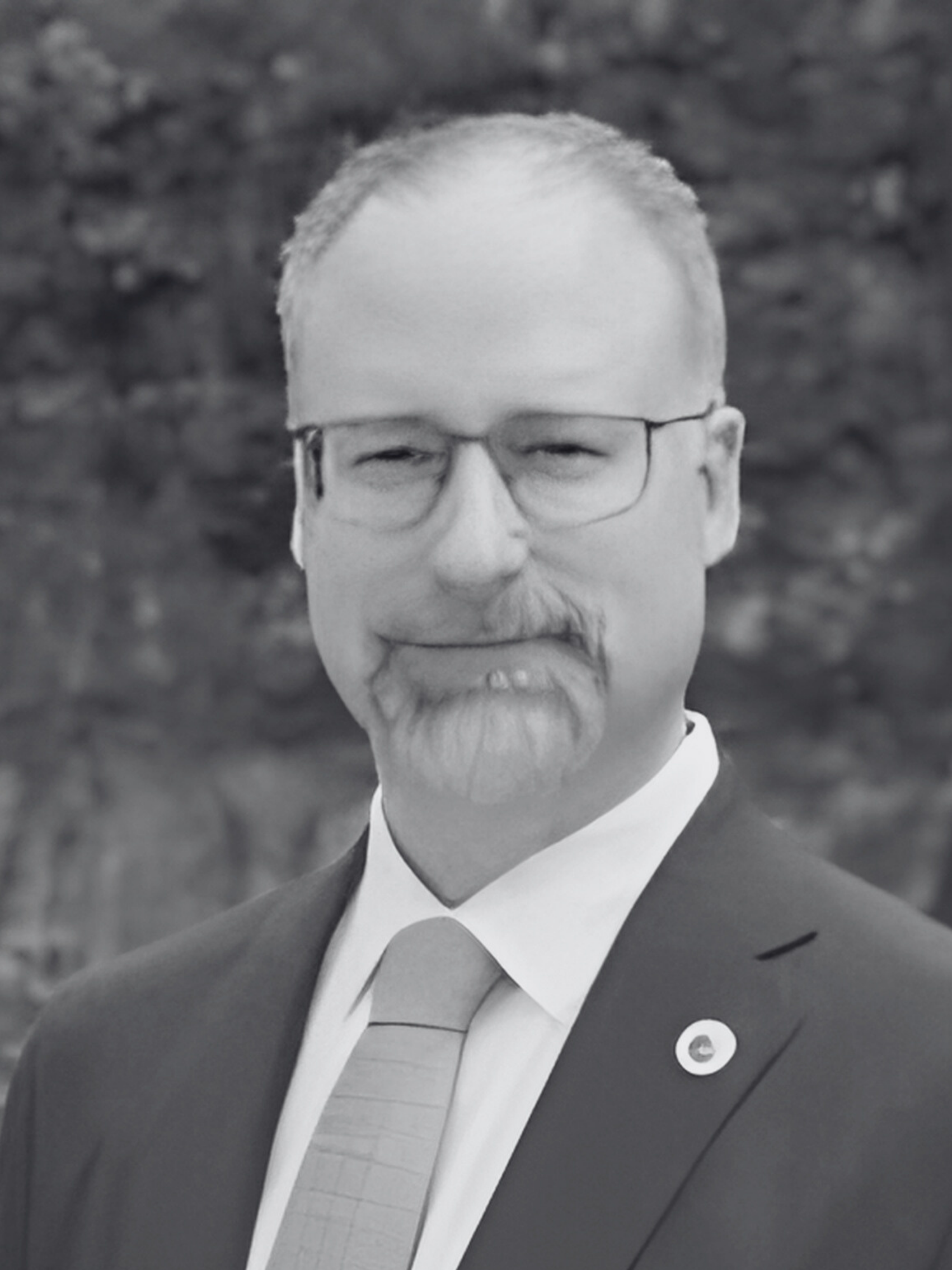 A man in a suit and tie is standing in front of a stone wall.