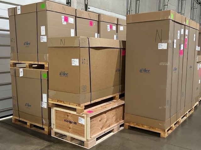 A group of workers are standing in front of a forklift in a warehouse.
