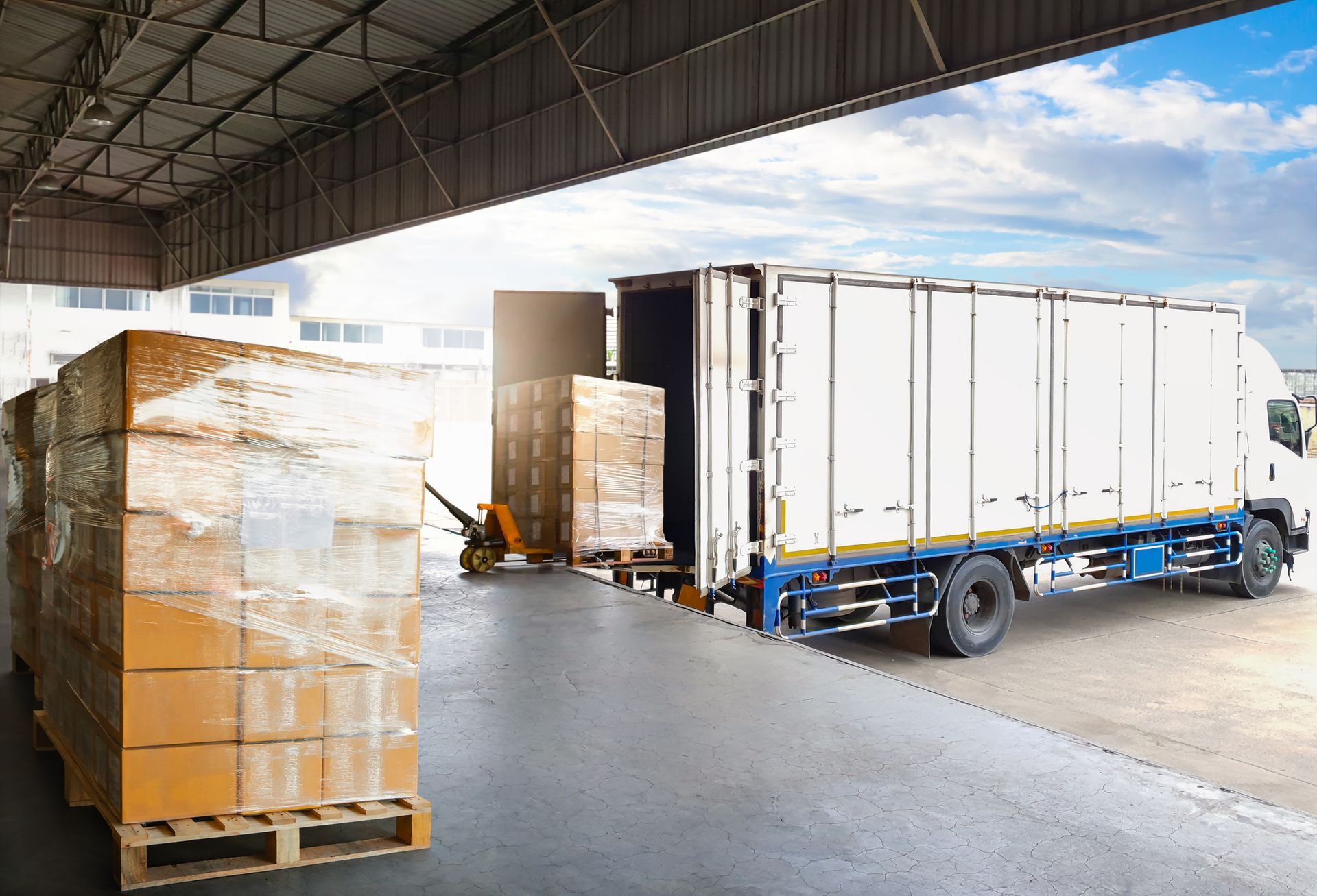 Two men are loading boxes into a van in a warehouse.