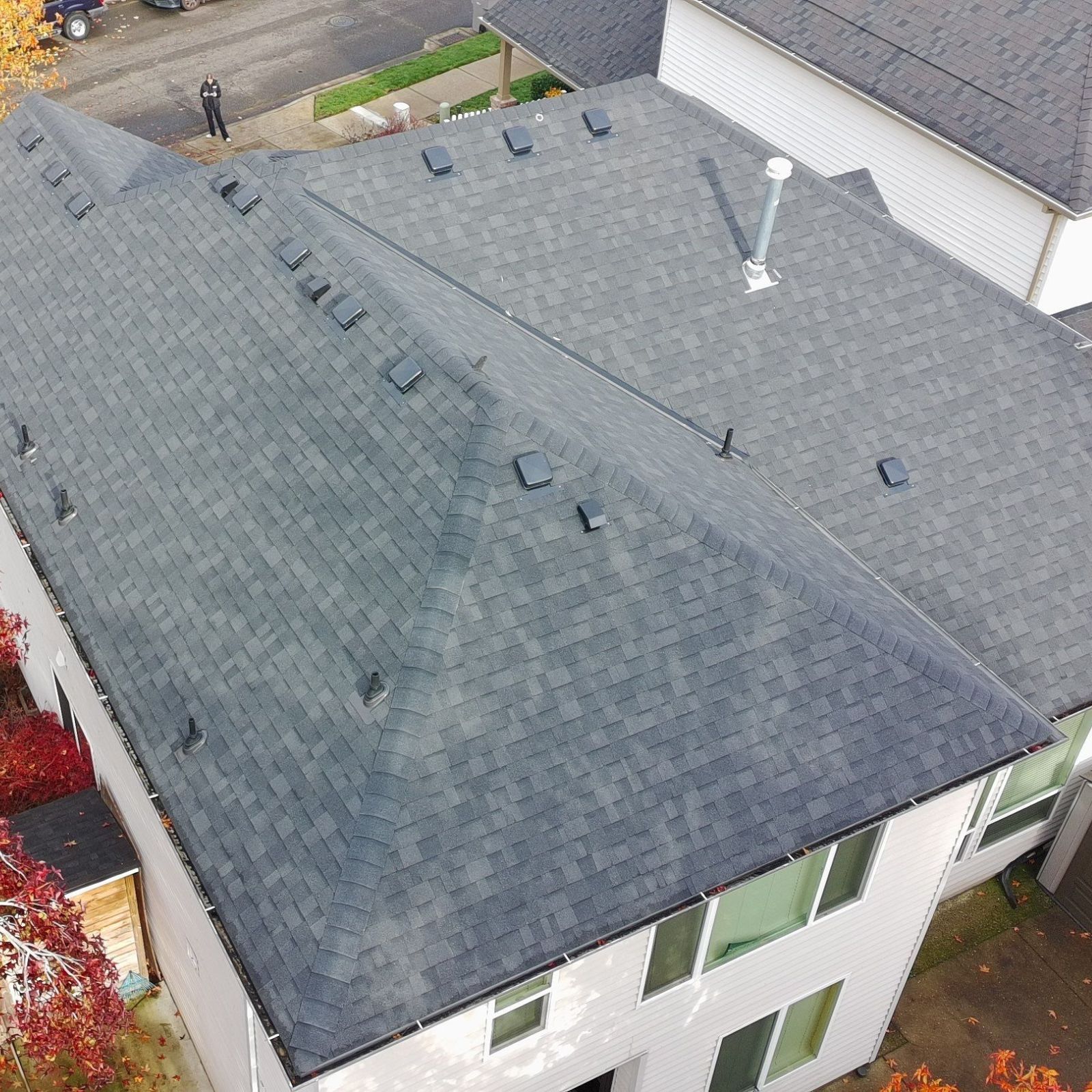 An aerial view of a duplex roof shows one side has been cleaned, revealing a contrast between dark, dirty and new shingles.