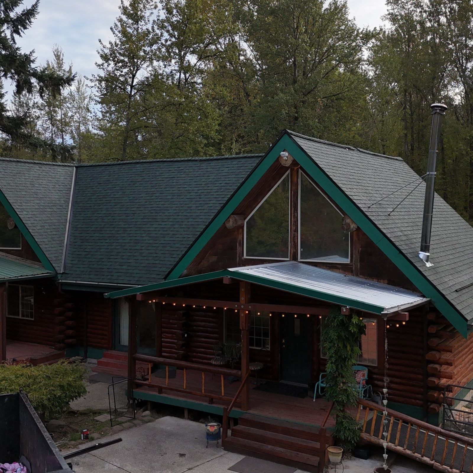 An aerial view of a steep gray-shingled roof with five small solar vents and a windowed gable on a residential house.