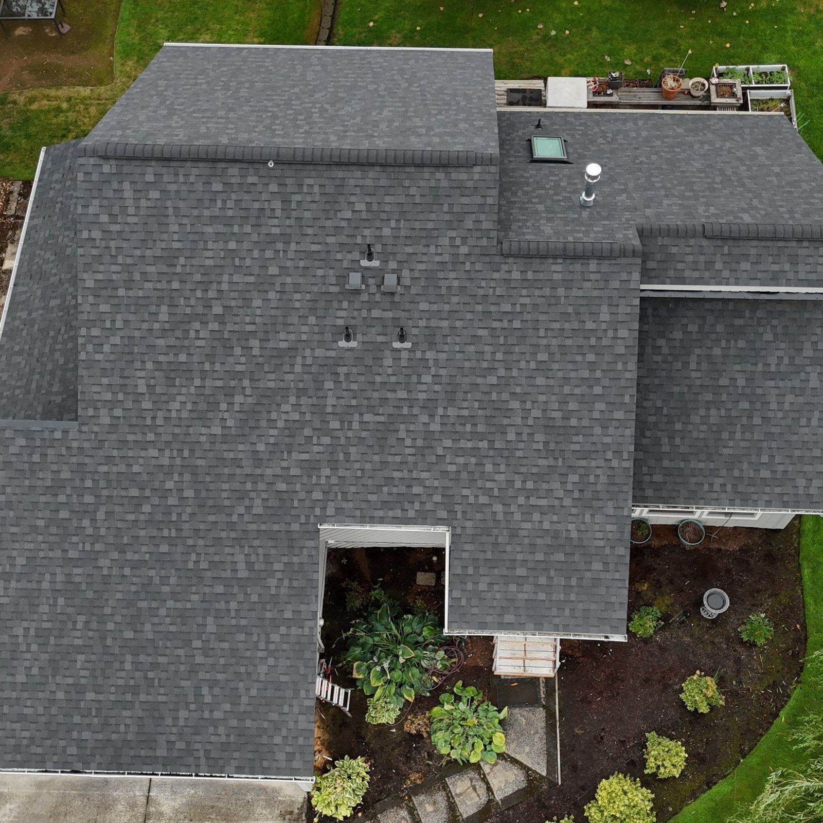 An aerial view of a white garage and house exterior with three toilets sitting on the front porch.