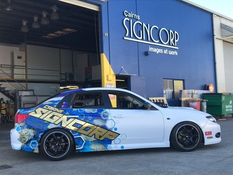 A White Car Is Parked In Front Of A Sign Corp Building — Cairns Signcorp In Portsmith, QLD