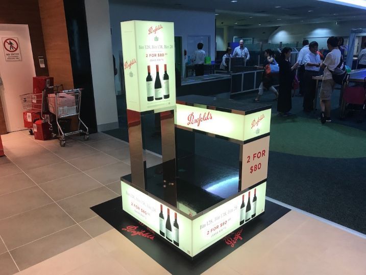 A Display Of Wine Bottles In A Store With People Standing In The Background — Cairns Signcorp In Portsmith, QLD