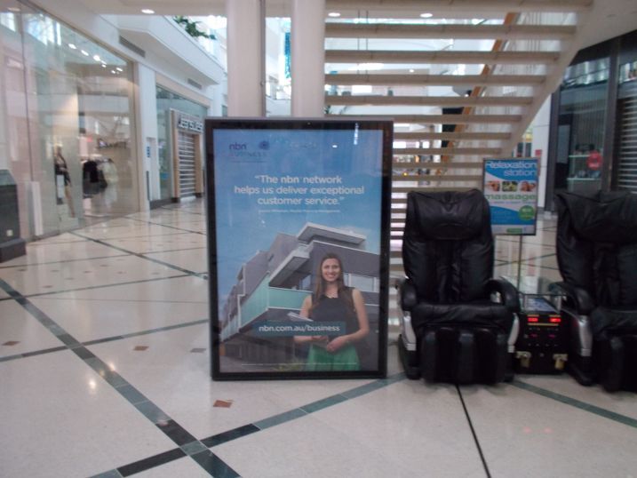 A Picture Of A Woman Standing Next To A Massage Chair In A Mall — Cairns Signcorp In Portsmith, QLD