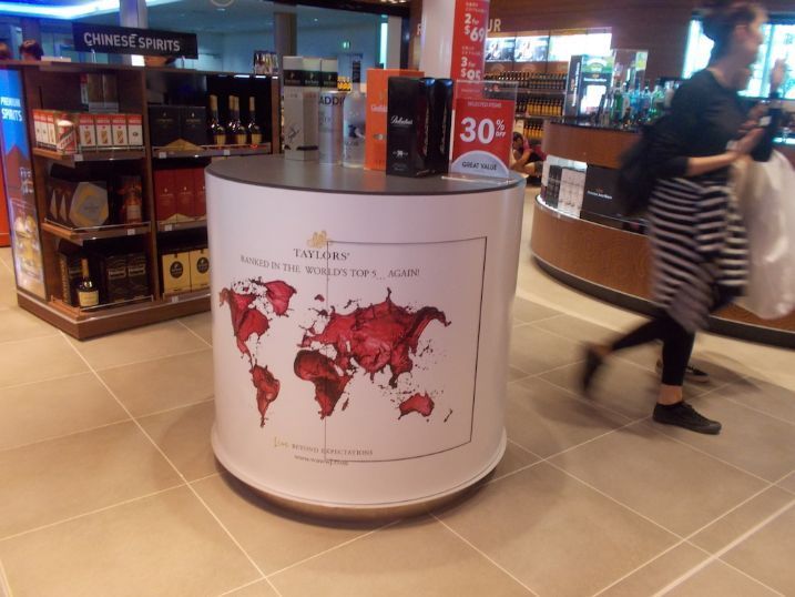 A Woman Is Walking Past A Table With A Map Of The World On It — Cairns Signcorp In Portsmith, QLD