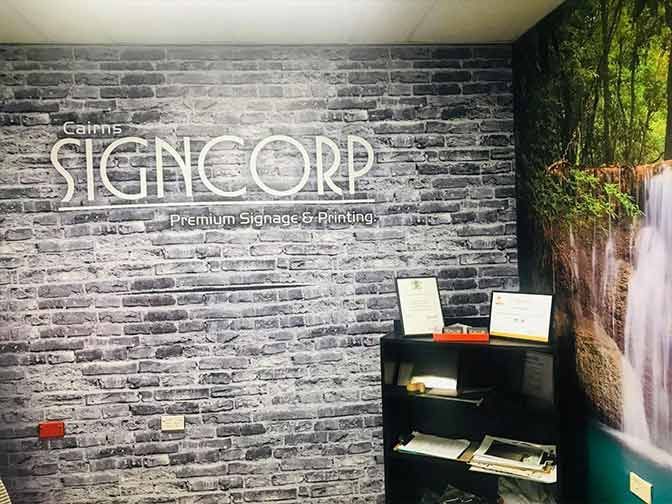 A Room With A Brick Wall And A Sign That Says Sign Corp — Cairns Signcorp In Portsmith, QLD