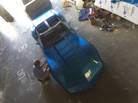 A Man Is Working On A Blue Car In A Garage — Cairns Signcorp In Portsmith, QLD