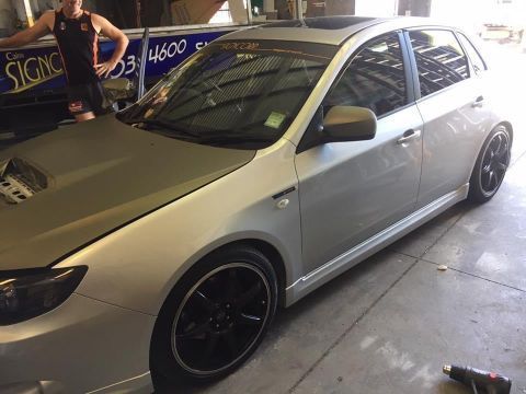 A Man Is Standing Next To A Silver Car In A Garage — Cairns Signcorp In Portsmith, QLD