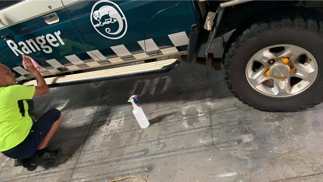 Man Cleaning A Green Ranger Truck's Side Panel In A Parking Area — Cairns Signcorp In Portsmith, QLD