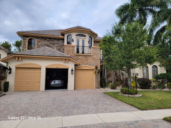 A car is parked in the driveway of a large house.