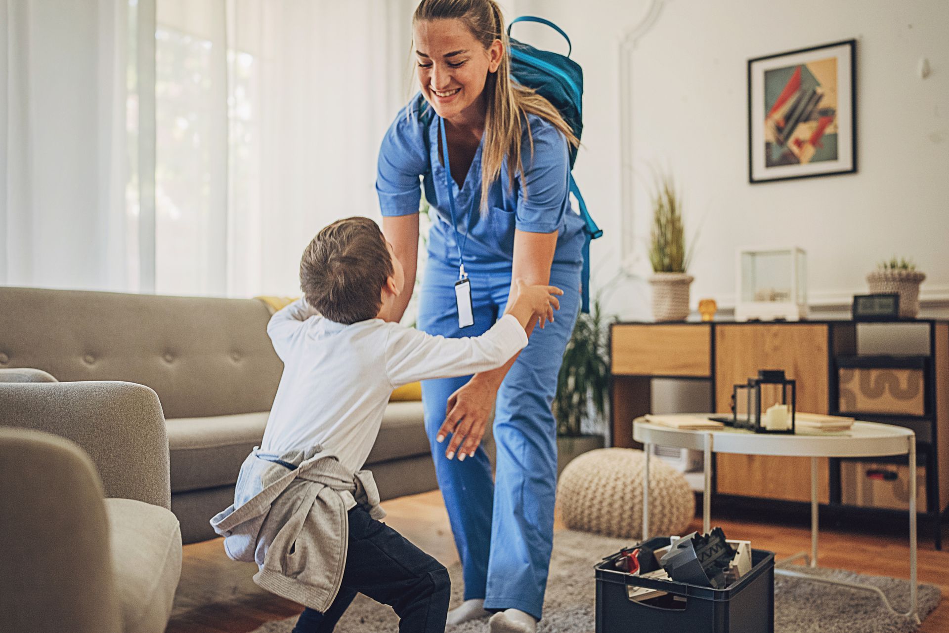A nurse is playing with a young boy in a living room.