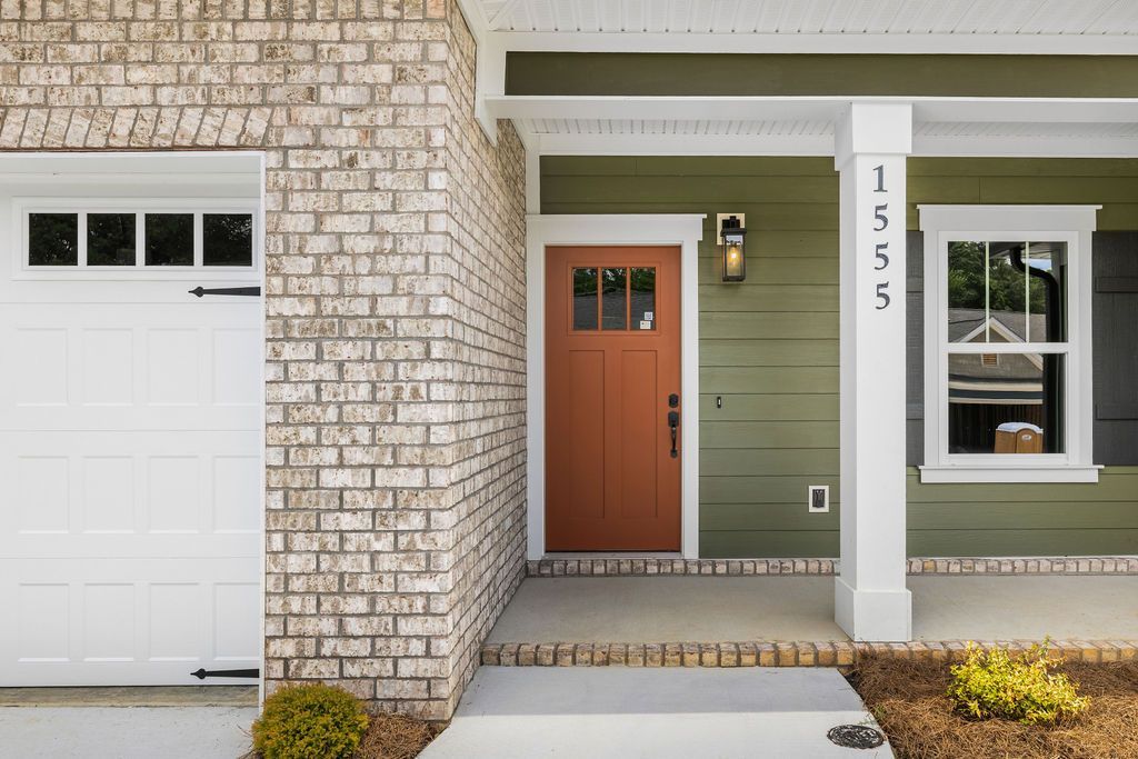 The front of a house with a red door and green siding.