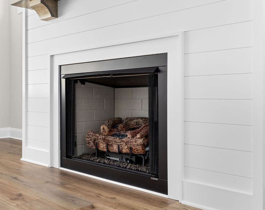 A fireplace with a black frame and a wooden mantle in a living room.