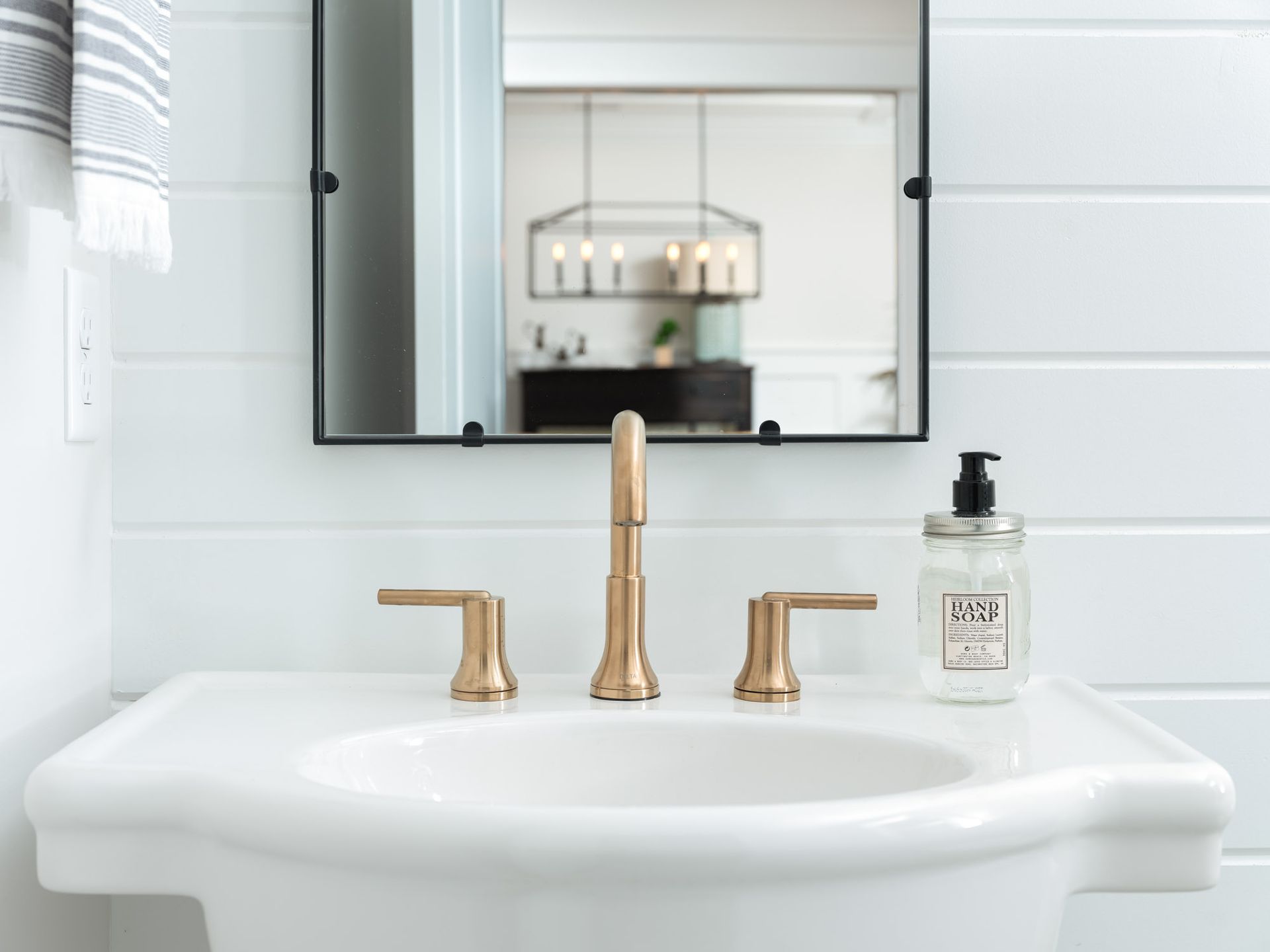 A bathroom sink with a gold faucet and a mirror.