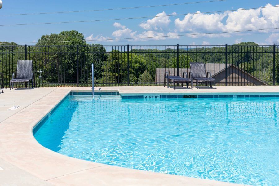 A large swimming pool surrounded by chairs and a fence.