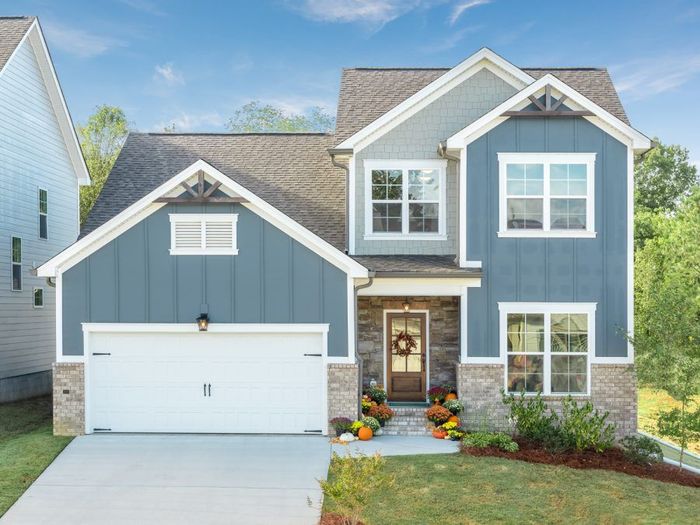 A blue and white house with a garage and a wreath on the door.
