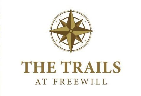 A logo for the trails at freewill with a compass on it