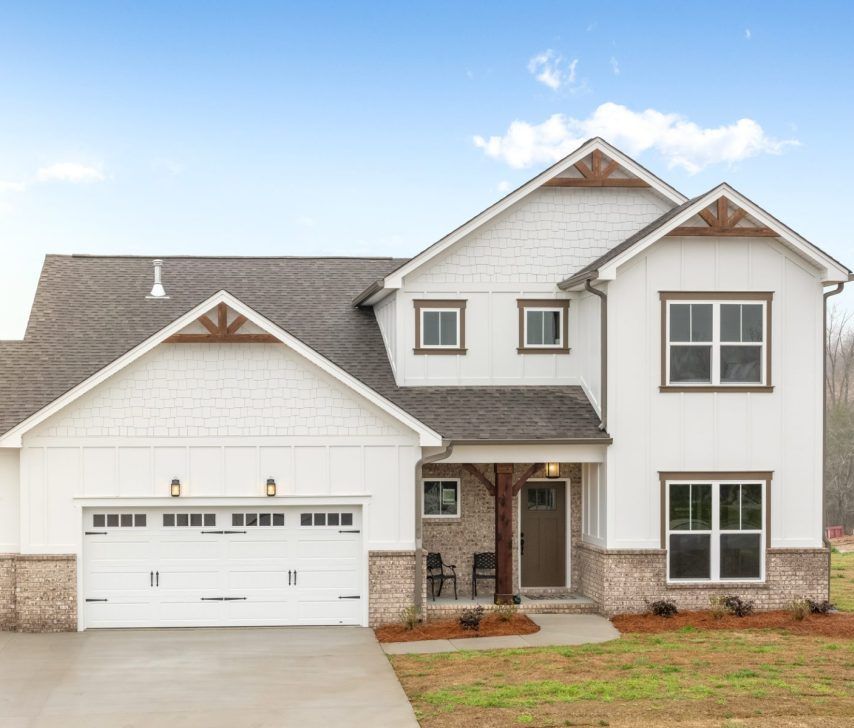 A large white house with a gray roof and a white garage door.