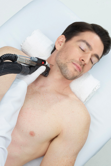 A shirtless man is getting a laser treatment on his neck