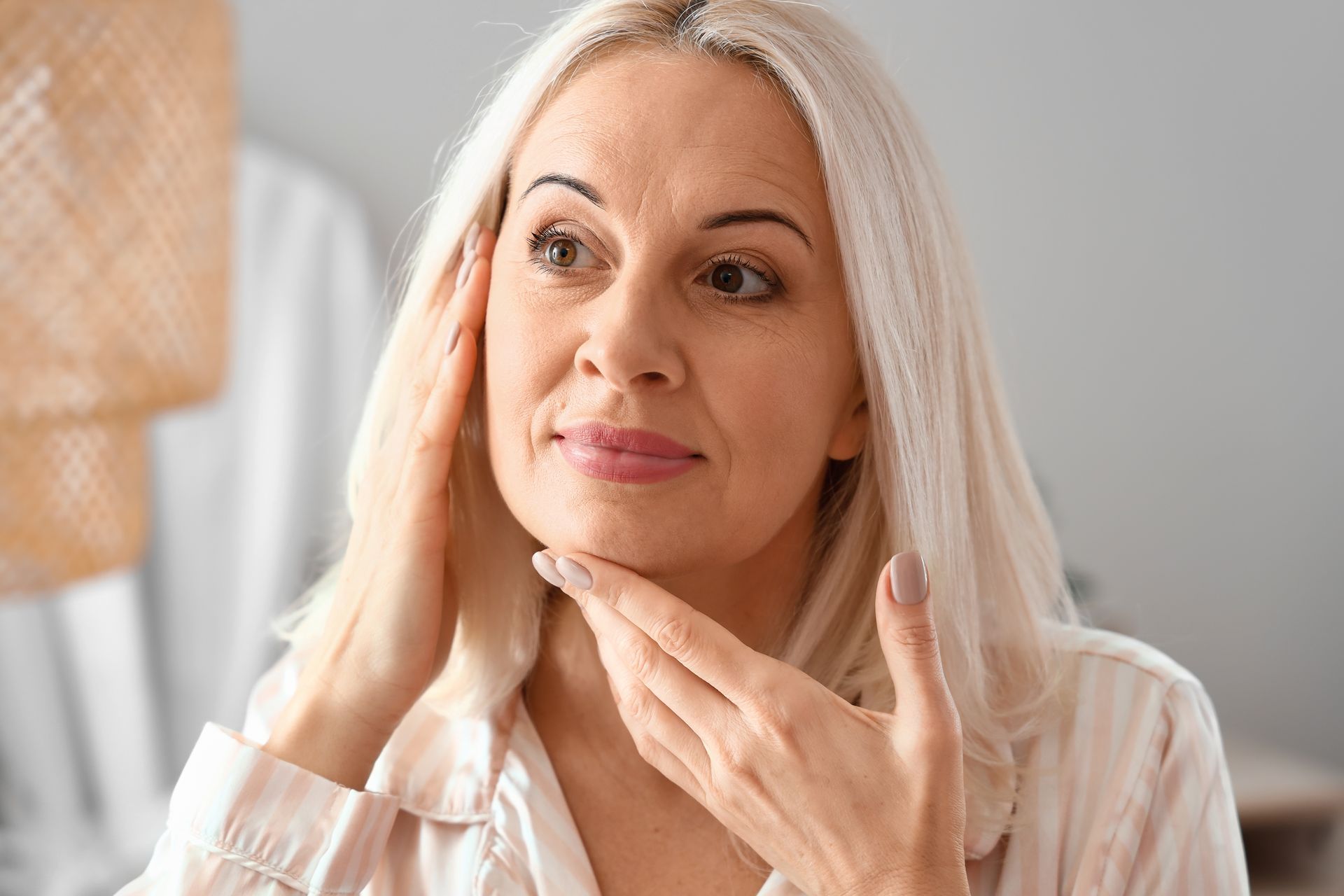 A woman is looking at her face in the mirror.