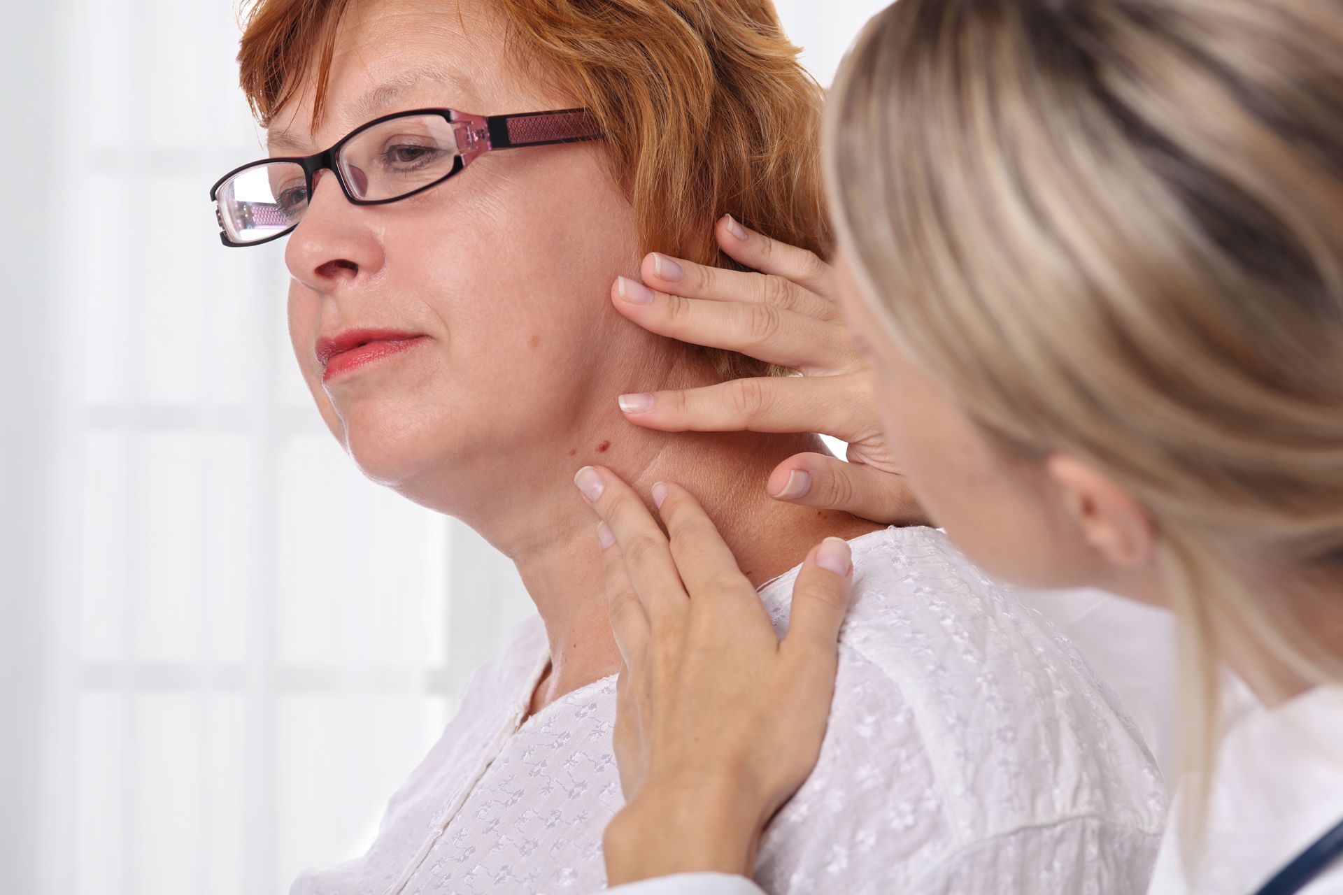 A doctor is examining a woman 's neck with a magnifying glass.