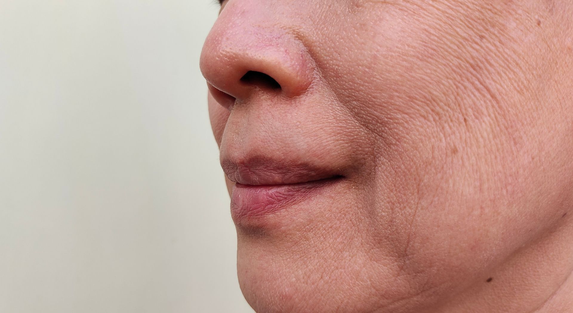 A close up of a woman 's face with wrinkles and a smile.