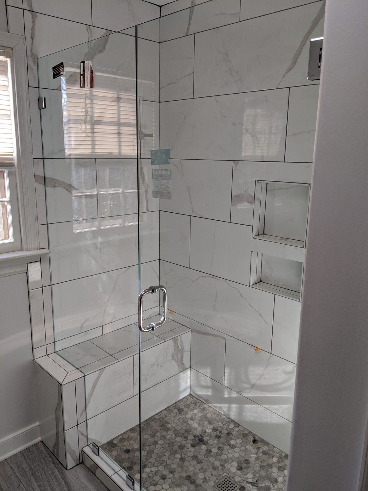 Glass shower enclosure with white tile walls and gray stone floor.