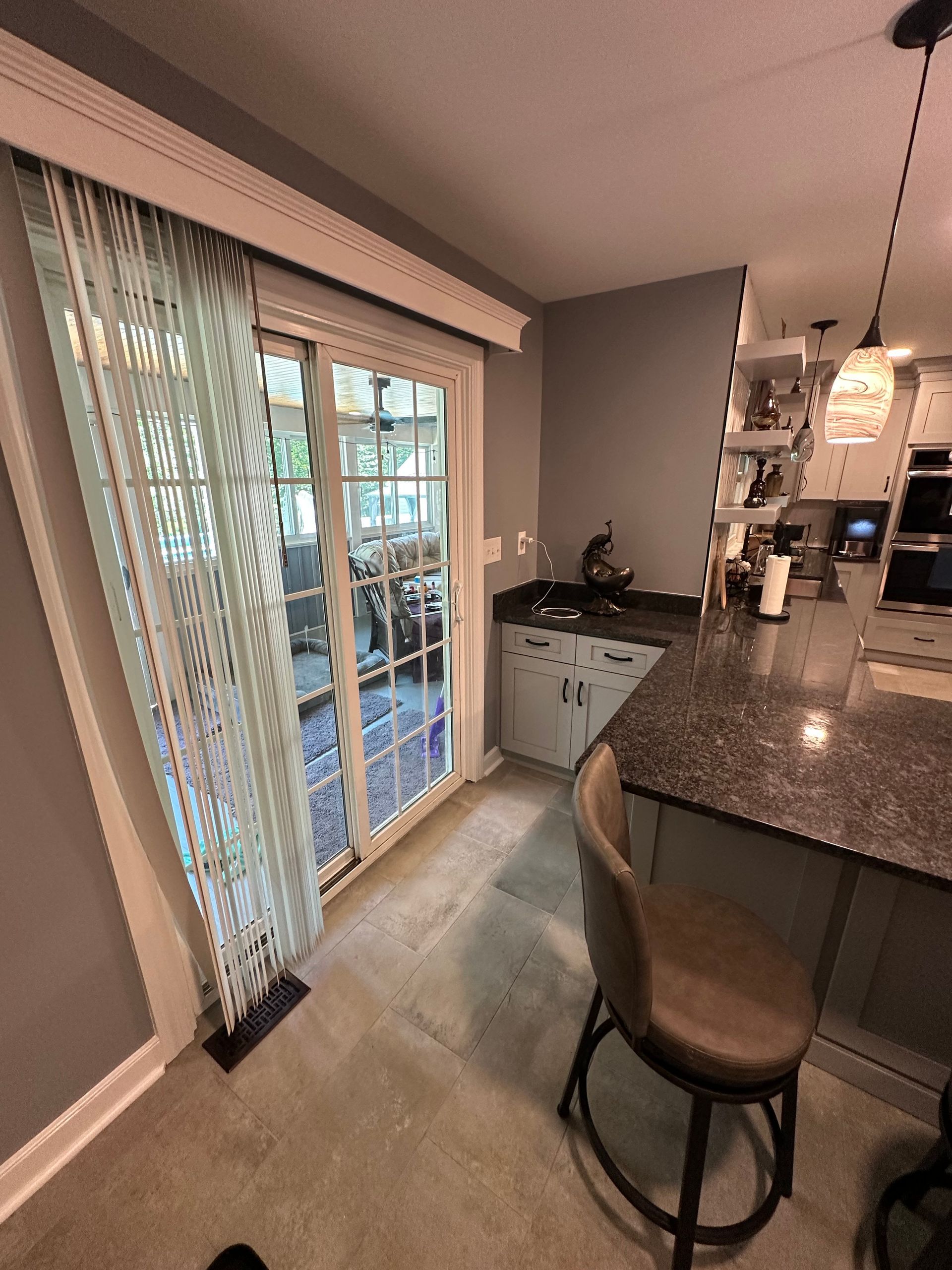 Kitchen with sliding glass door, bar seating, cabinets, and a concrete floor.