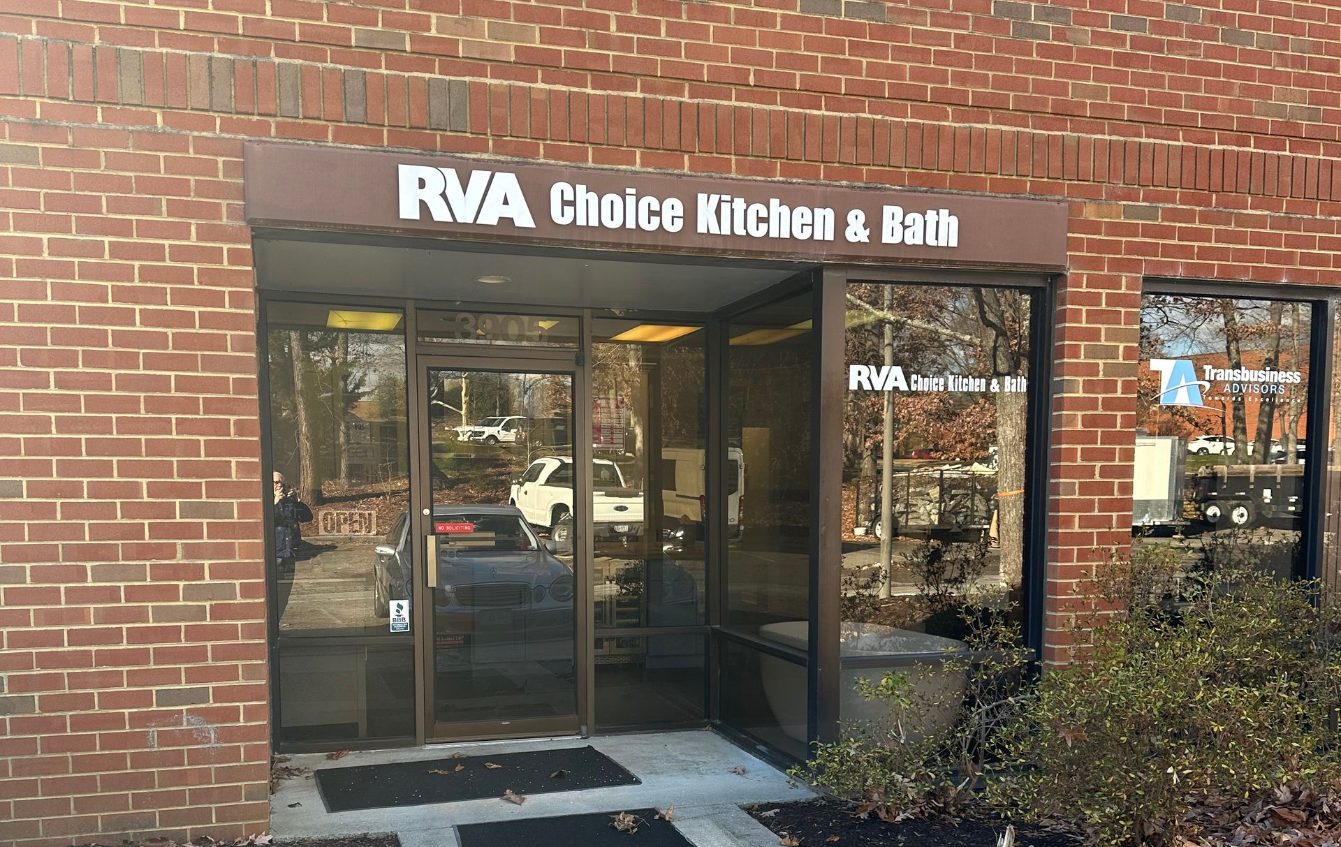 Entrance to RVA Choice Kitchen & Bath, a building with red brick exterior and glass doors.