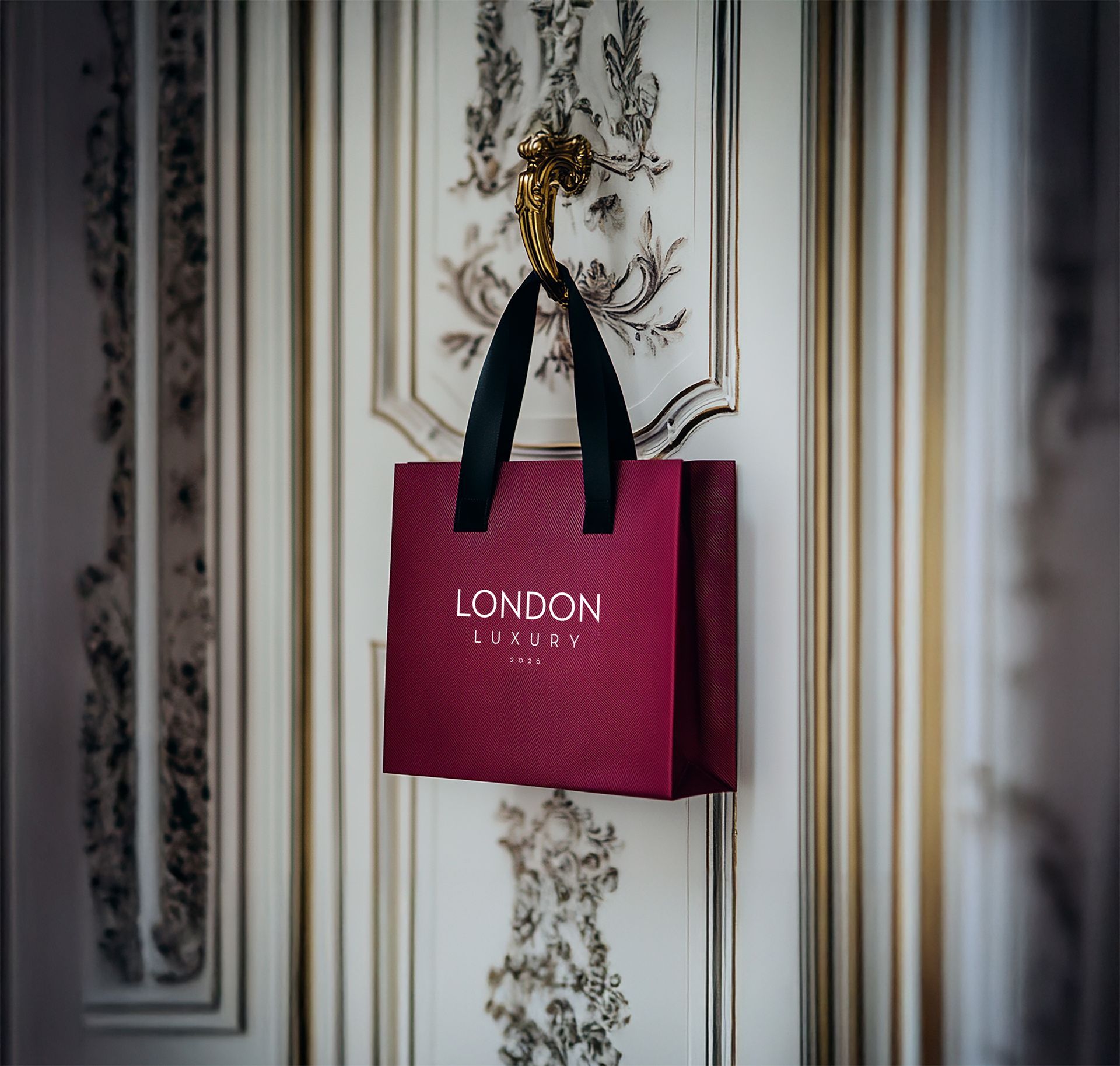 A pink london bag hangs on a door handle