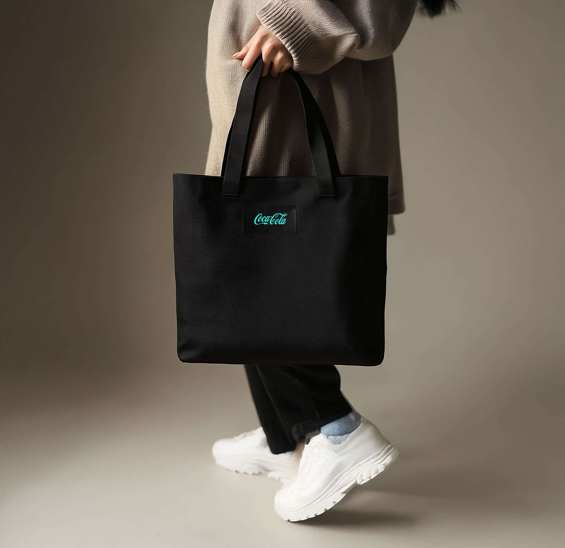 A woman is holding a black tote bag that says crese on it