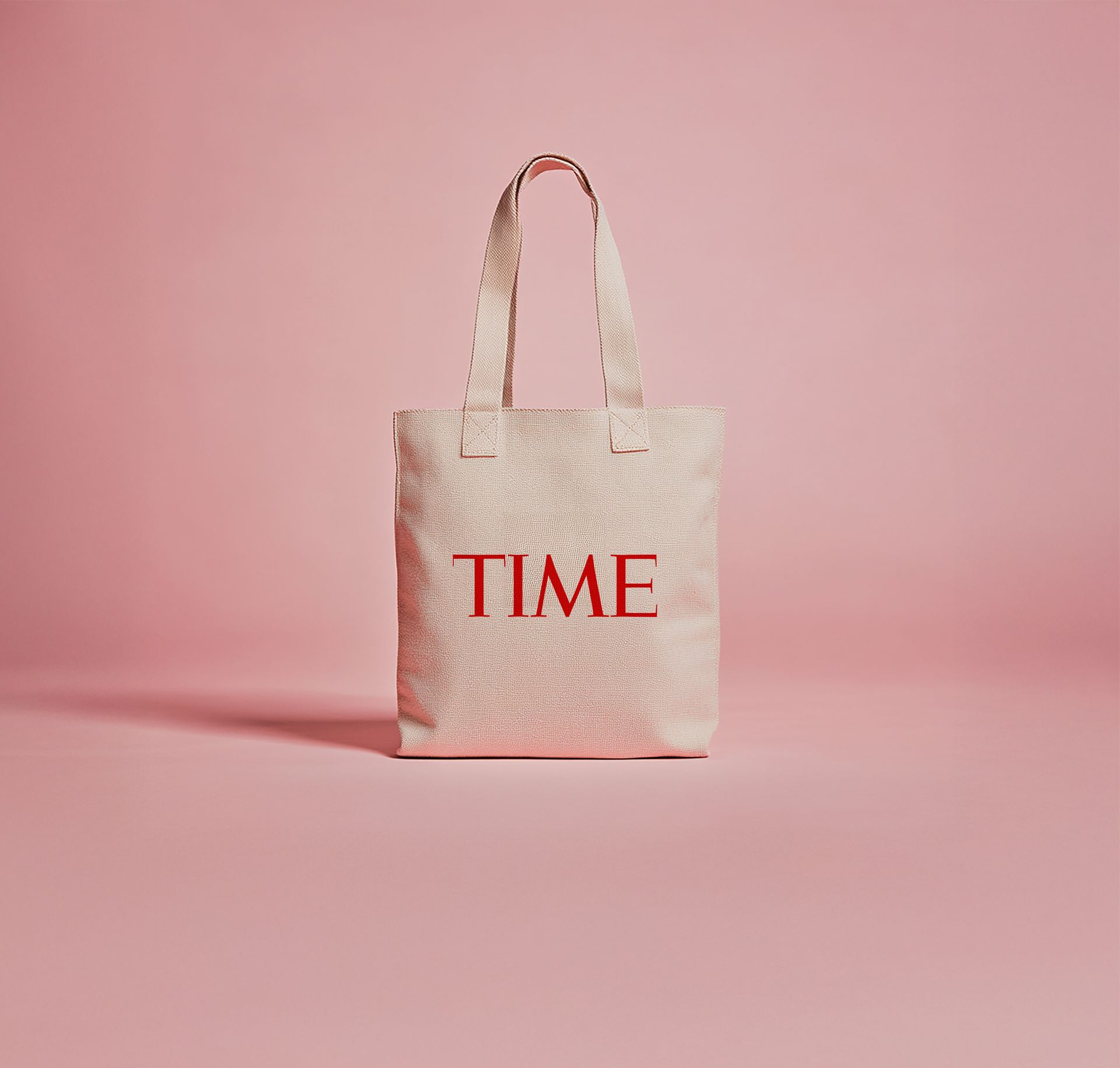 A tote bag with the word time written on it is sitting on a pink surface.
