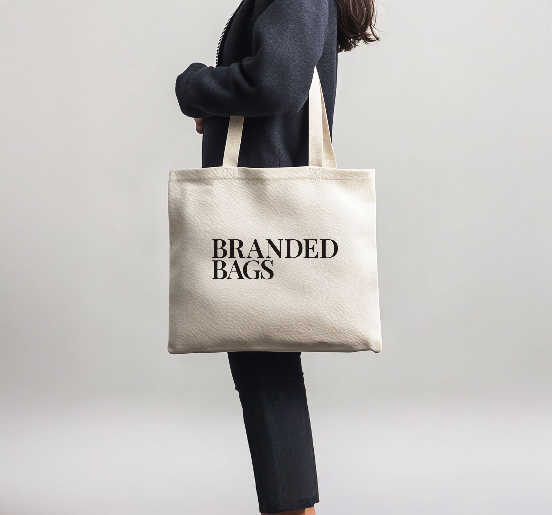 A woman is holding a tote bag that says branded bags