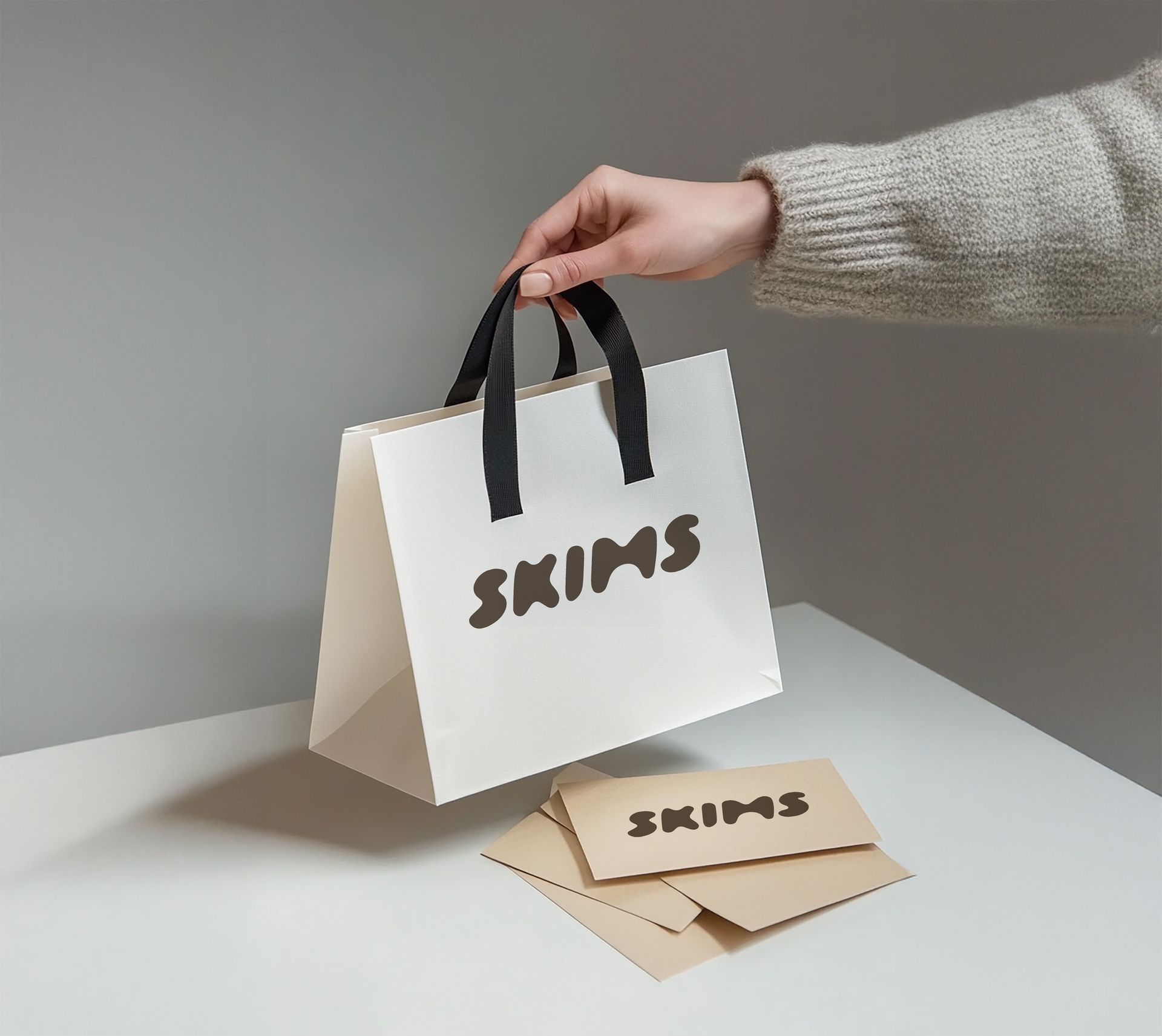 A person is holding a white bag that says skims on it