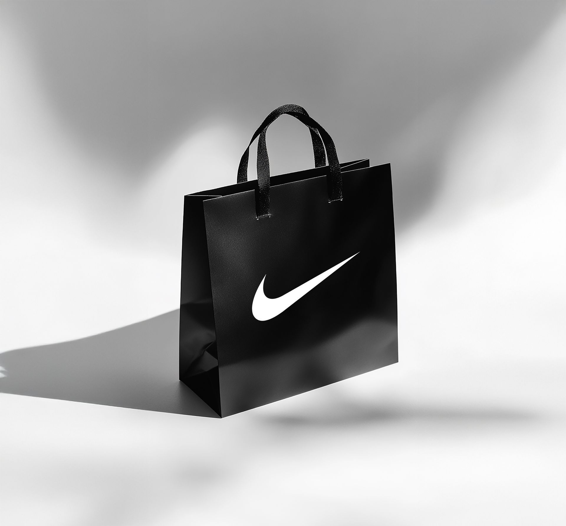 A black nike shopping bag is sitting on a white surface