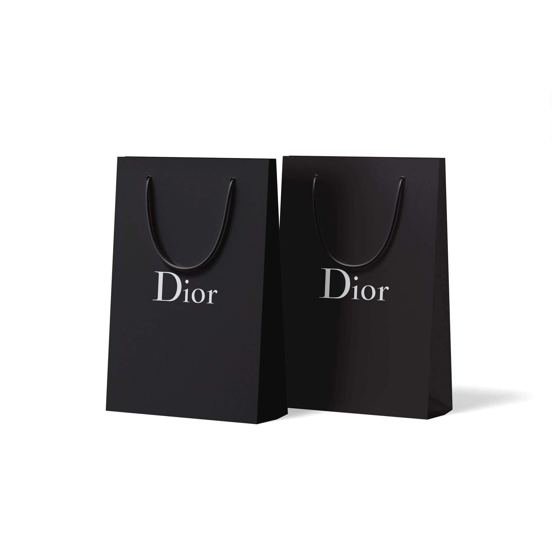 Two black dior shopping bags with handles on a white background.