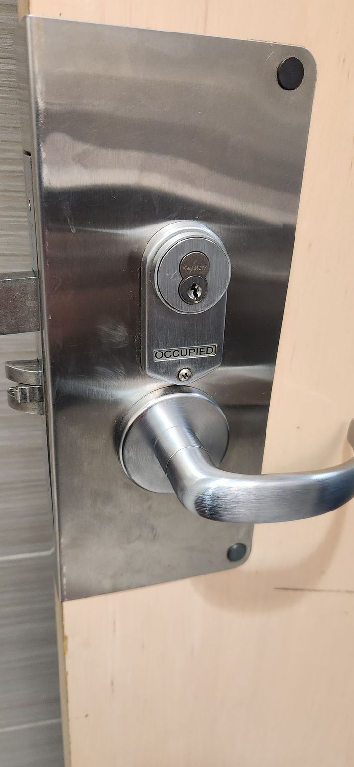 A man is holding a bunch of keys in a door lock.